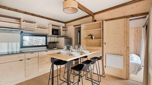 Eine kompakte Küche mit Holzausstattung, einer eingebauten Mikrowelle und einem Essbereich mit Sitzgelegenheiten.