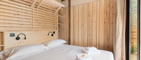 A wooden cabin-style bedroom with a bed, pillows, and towels.