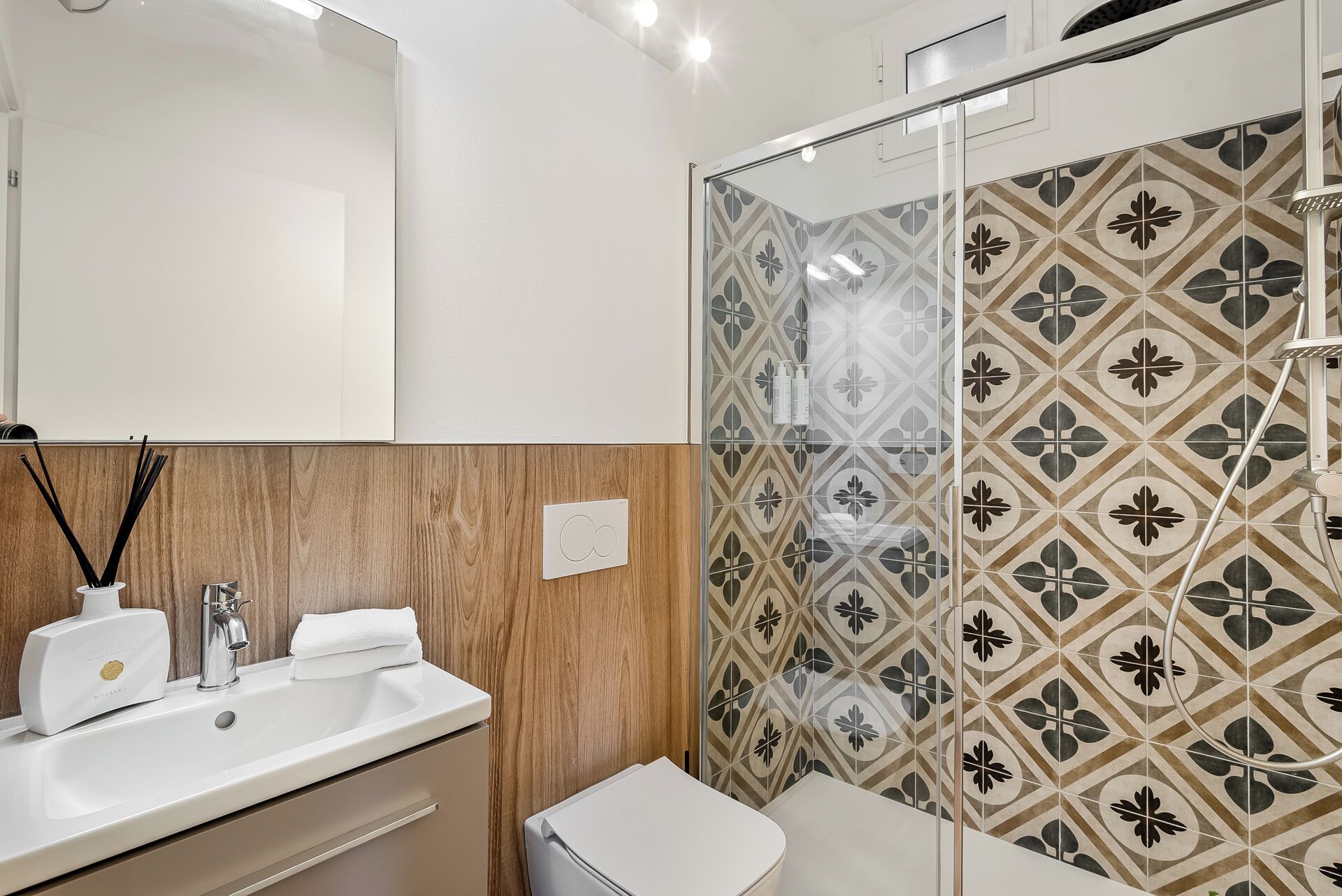 Une salle de bain moderne avec un meuble-lavabo en bois, un lavabo blanc et une douche aux carreaux décoratifs.
