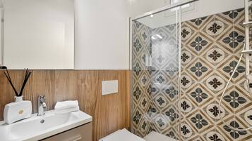 Une salle de bain moderne avec un meuble-lavabo en bois, un lavabo blanc et une douche aux carreaux décoratifs.