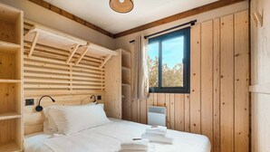 Ein Zimmer mit Holzboden, einem Bett, einem Fenster und einem Deckenventilator.