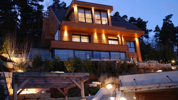 Une maison moderne à deux étages, dotée d’un escalier en pierre menant à une terrasse en bois.
