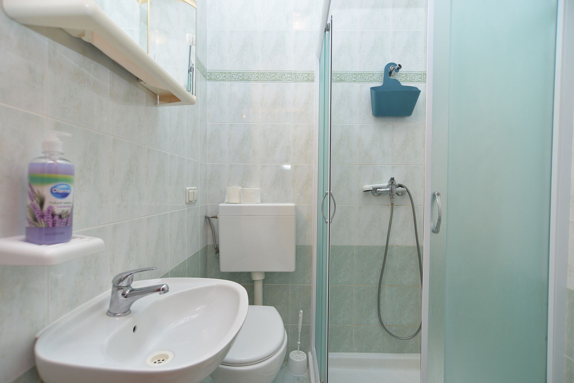 Un bagno con lavandino bianco, WC e cabina doccia in vetro.
