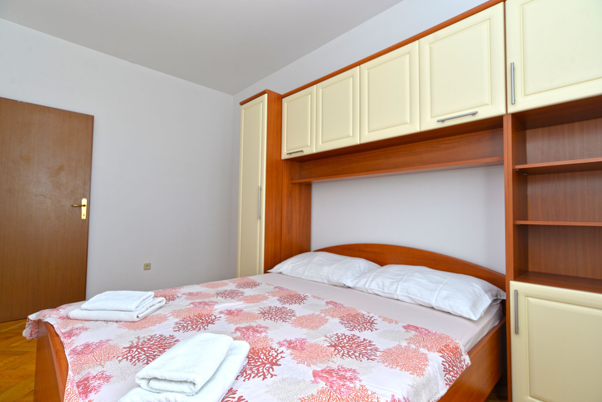 Un dormitorio con cama, cabecera de madera y estanterías empotradas.