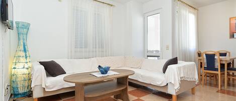 A room with a sofa, a coffee table, a TV, and a lamp.
