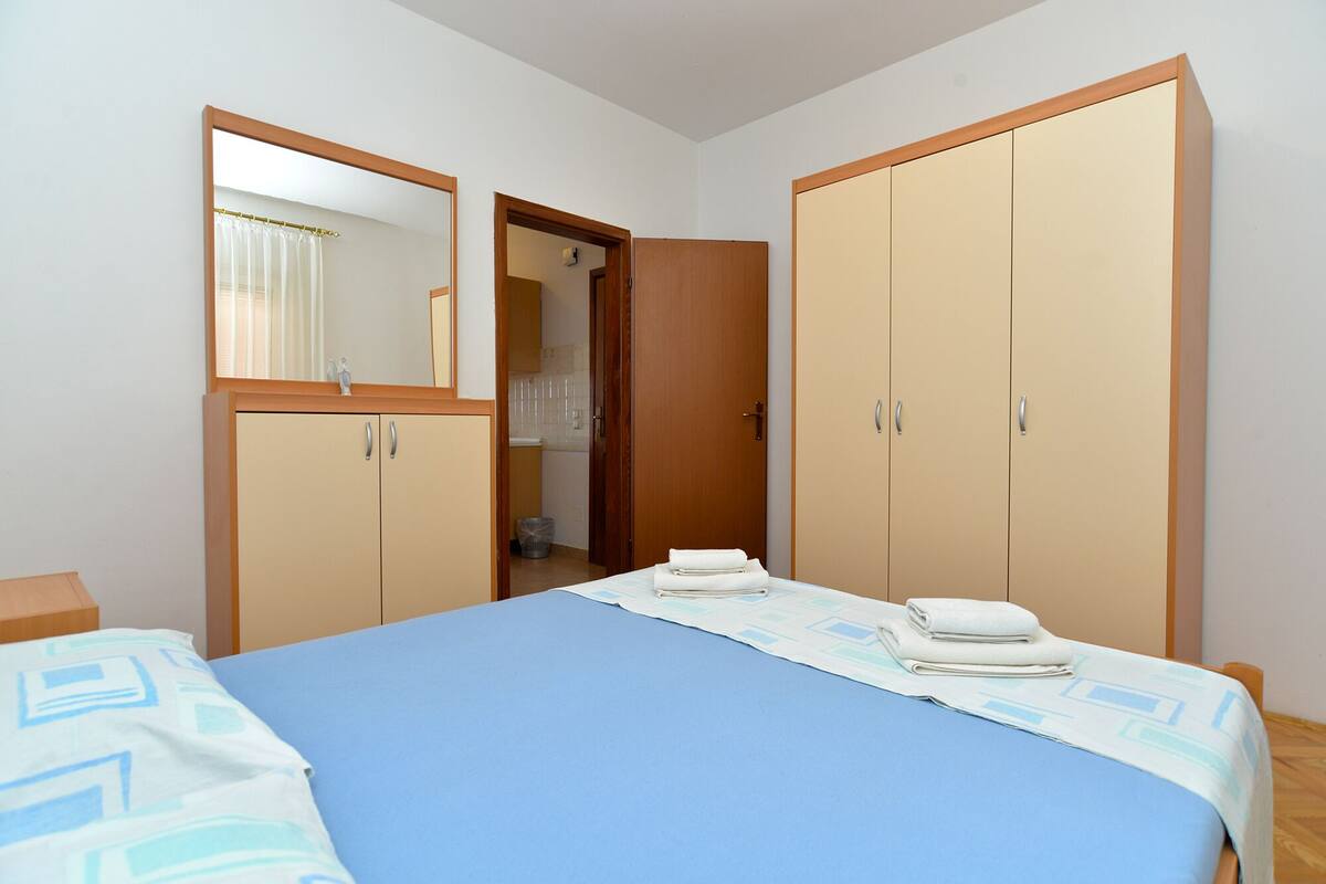 A bedroom with a bed, two wardrobes, a mirror, and a bathroom visible through an open door.