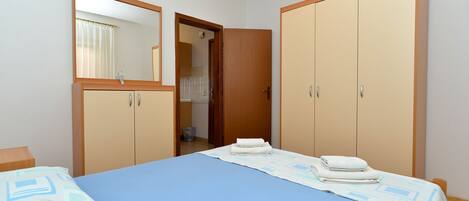 A bedroom with a bed, two wardrobes, a mirror, and a bathroom visible through an open door.