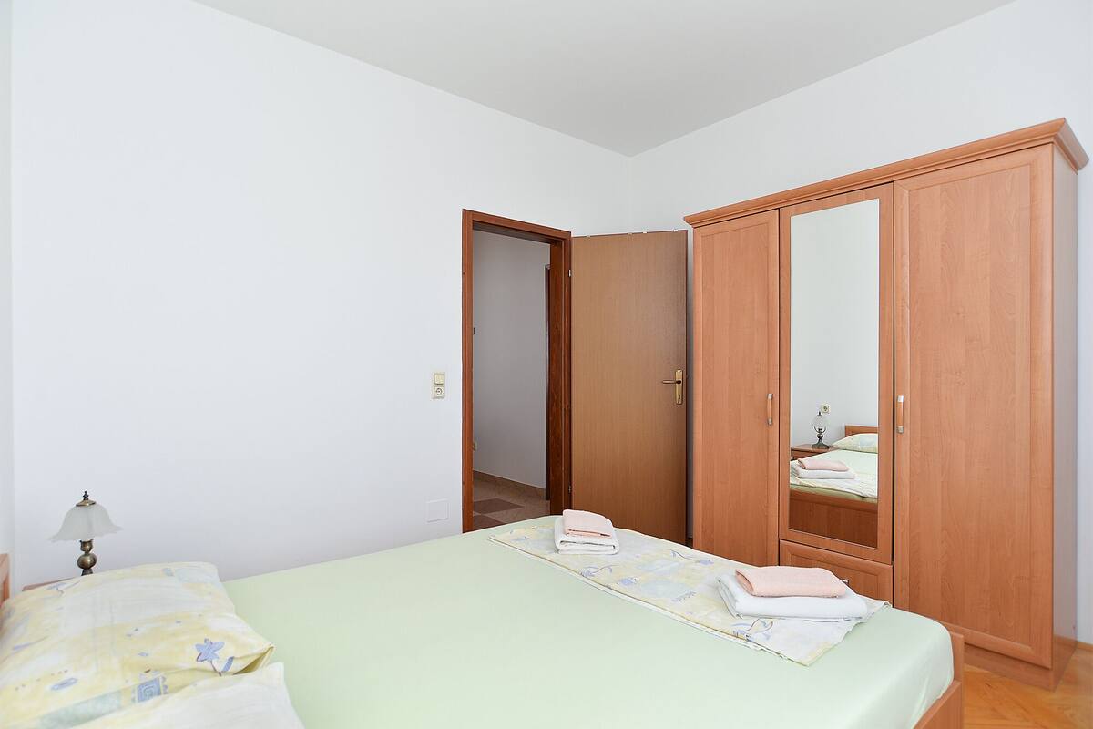 A bedroom with a bed, a wardrobe, and a nightstand with a lamp.