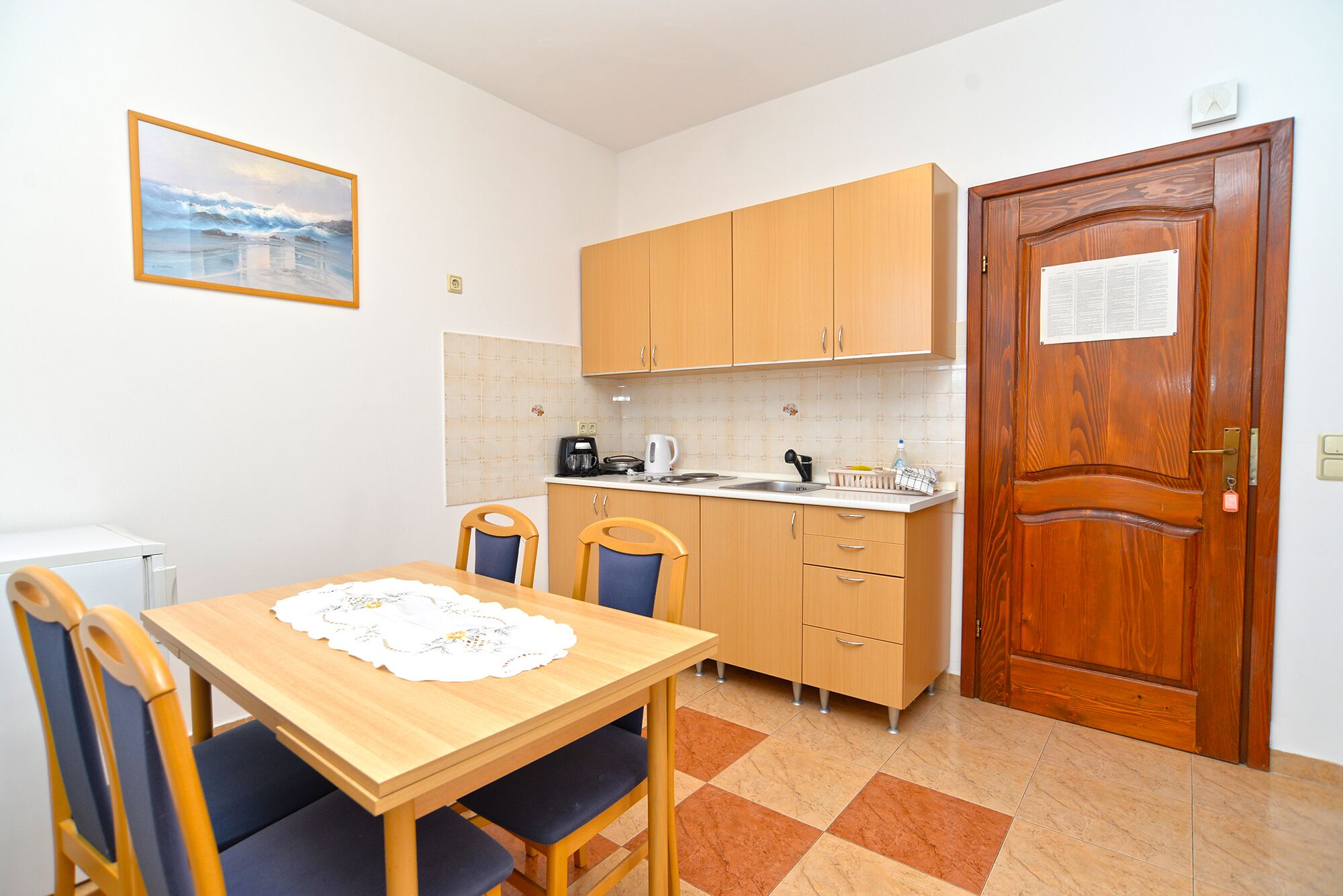 Una cocina pequeña con armarios de madera, un lavamanos y una mesa de comedor con sillas.