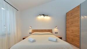 Un dormitorio moderno con una cama grande, cabecero de madera y dos mesitas de noche.