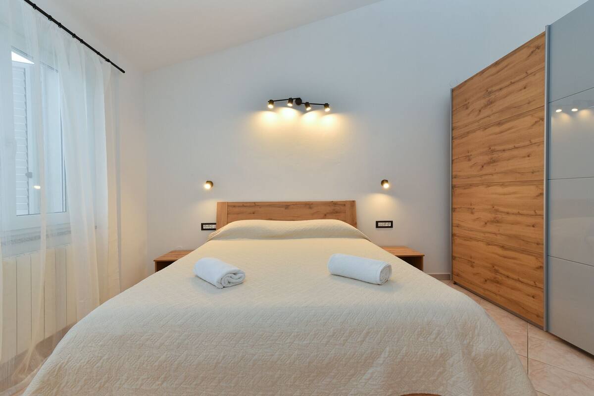 A modern bedroom with a large bed, wooden headboard, and two bedside tables.