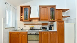 Una cocina con armarios de madera, estufa, lavamanos y refrigerador.