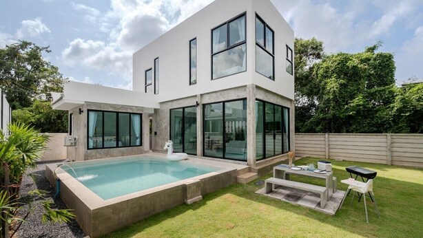 A modern two-story house with a swimming pool, a patio with a table and chairs, and a well-maintained lawn. - Gina Poolvilla89 Pattaya-Bangsaray beach (Sattahip)