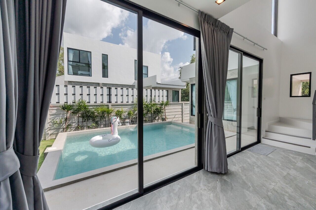 A modern interior with a large sliding glass door leading to a swimming pool area.