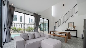 A modern living room with a sectional sofa, a wooden bench, and a staircase. - Gina Poolvilla89 Pattaya-Bangsaray beach (Sattahip)