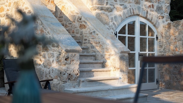 A stone staircase leading to a white door with a window, surrounded by stone walls. - Heritage Vila malena (Vir)