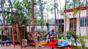 A playground with swings, slides, and a yellow toy airplane. - Tectona Treetop Mansion (Hyderabad)