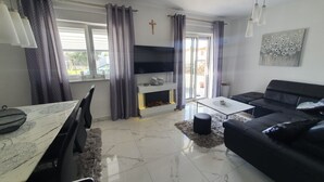 Uma sala de estar moderna com um sofá preto, uma mesa de jantar e uma lareira.