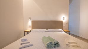 A hotel room with a neatly made bed, two bedside tables, and a headboard.