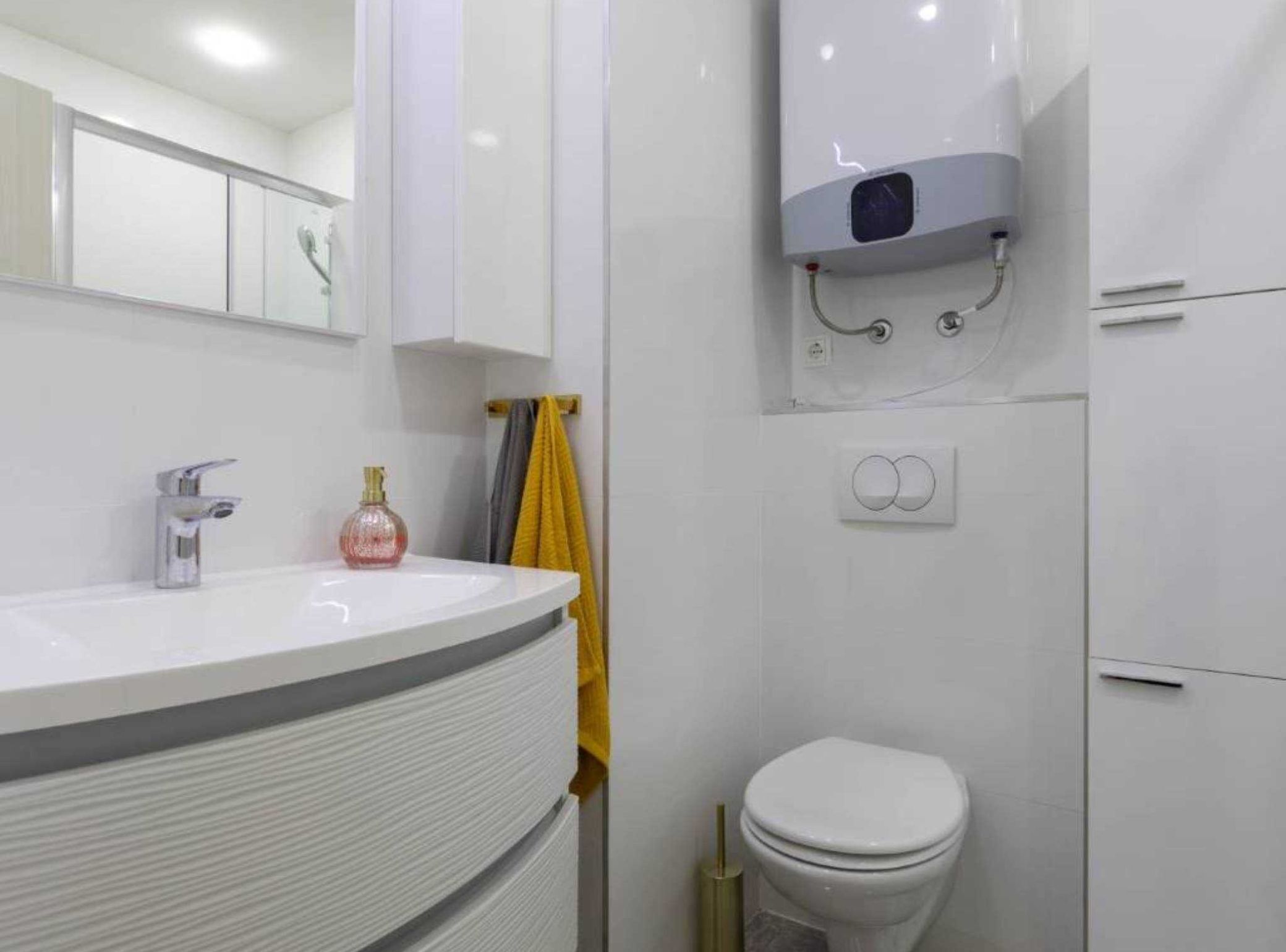 A modern bathroom with a white sink, a toilet, and a shower area.