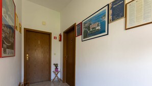 A hallway with two wooden doors, a small table with a potted plant, and framed pictures on the walls. - Bright and Spacious Apartment With Terrace in Kastel Stafilic (Kastela)