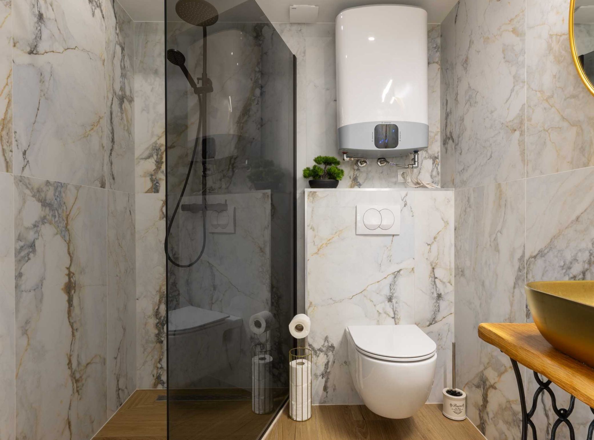 A modern bathroom with a glass-enclosed shower, a toilet, and a sink area.