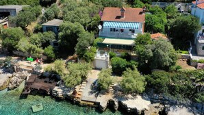 An aerial view of a coastal property with a large house featuring a tiled roof, a balcony, and a satellite dish. - Holiday Home by the Sea With Terrace & Ocean Views on Čiovo (Okrug)