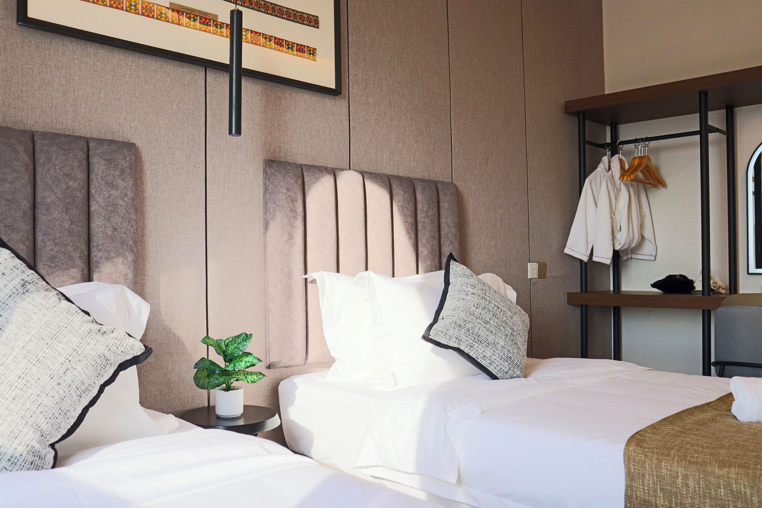 A hotel room with a large bed, a bedside table with a plant, and a wardrobe with a mirror.