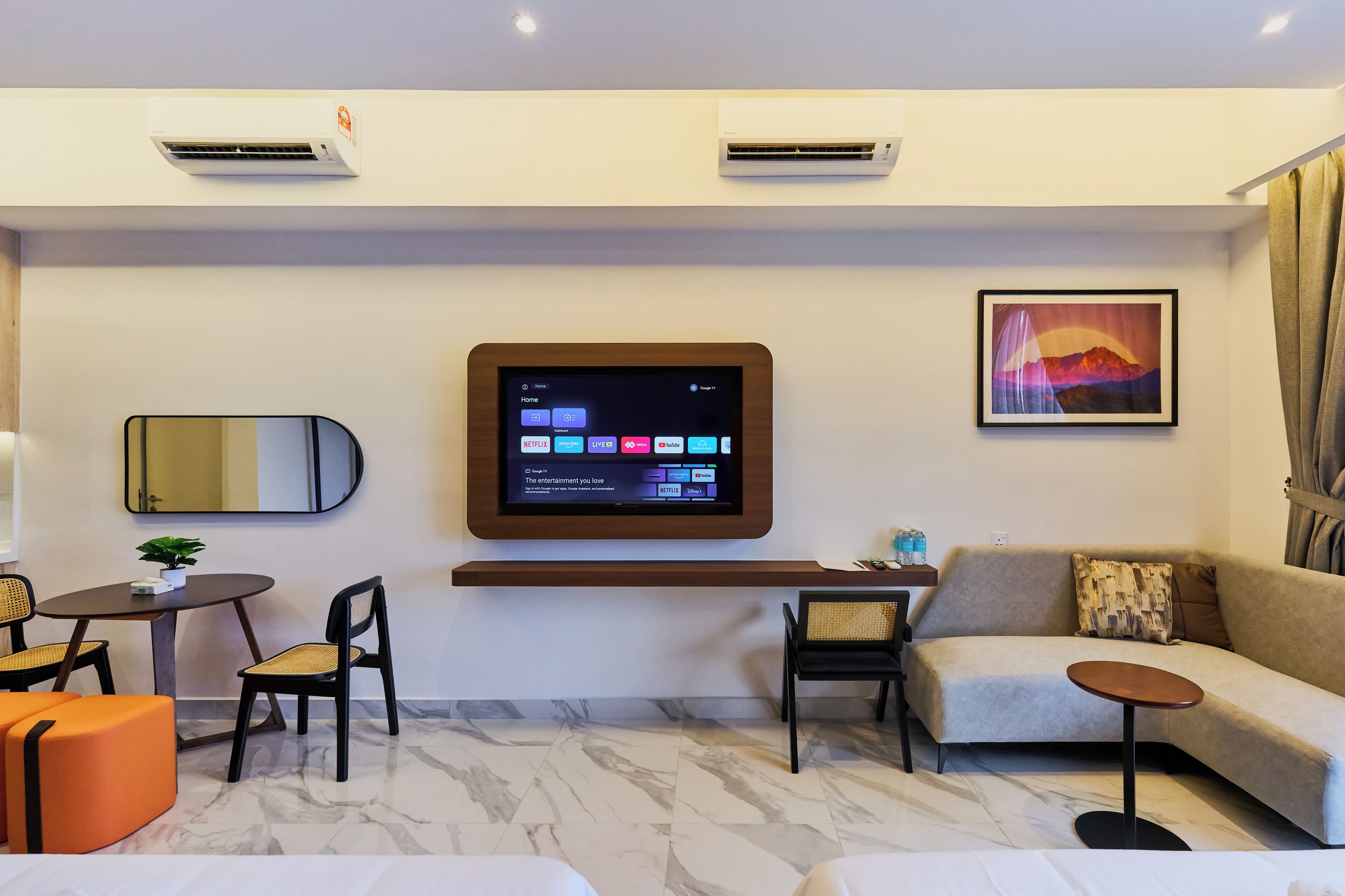Una habitación de hotel moderna con una televisión de pantalla plana, un sofá, una mesita y una silla.