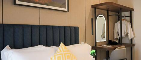 A hotel room with a bed, a desk with a mirror, and a framed picture on the wall.