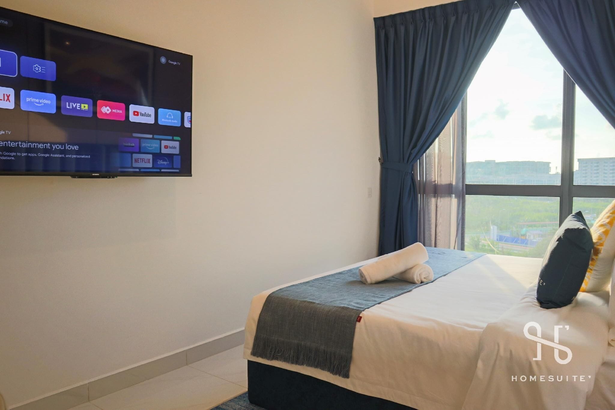 Een hotelkamer met een bed, een aan de muur bevestigde televisie waarop verschillende streamingdiensten te zien zijn, en een raam met gordijnen.