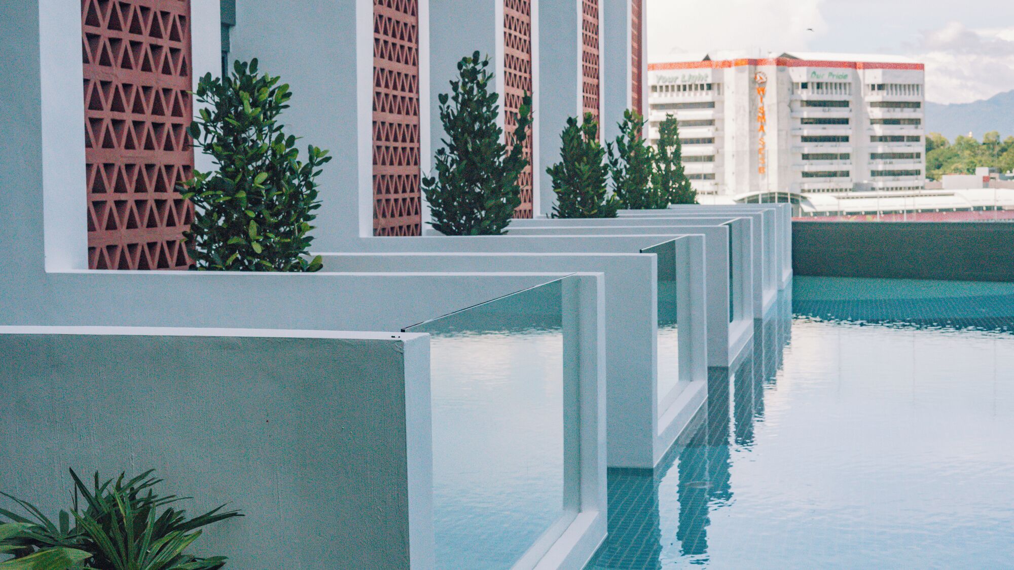 A modern pool area with geometric poolside barriers and potted plants.