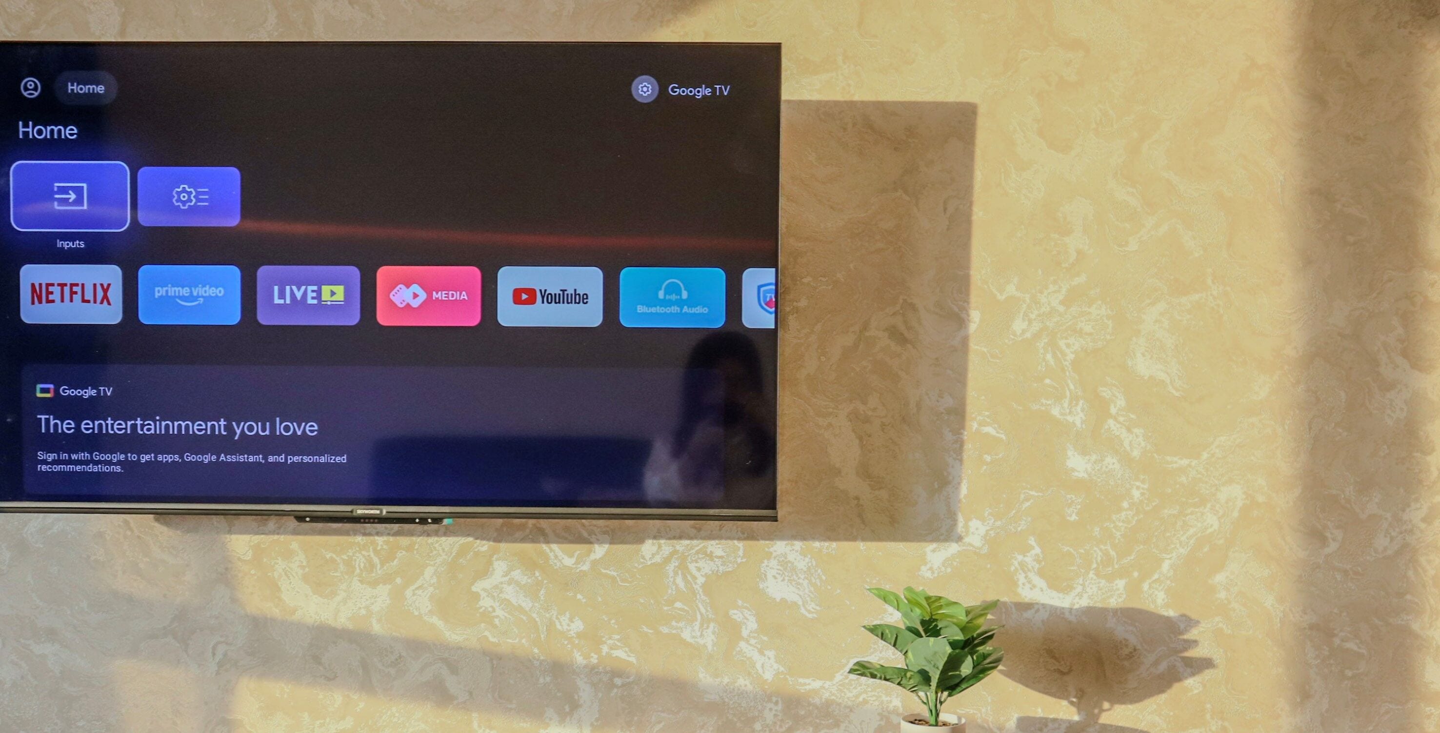 A flat-screen TV mounted on a wall with a patterned wallpaper background.