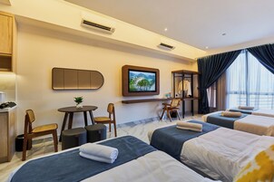 Habitación de hotel con dos camas, un escritorio, una silla, una mesita, un televisor y una ventana con cortinas.
