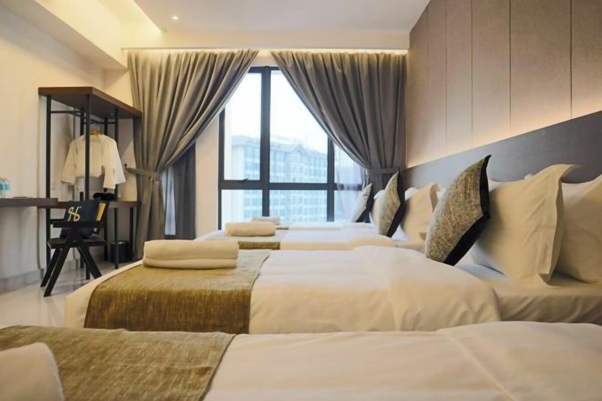 A hotel room with two beds, a desk, and a window with curtains.