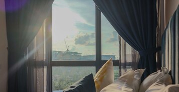 Una habitación con un ventanal grande, una cama con almohadas y vista a un barco.
