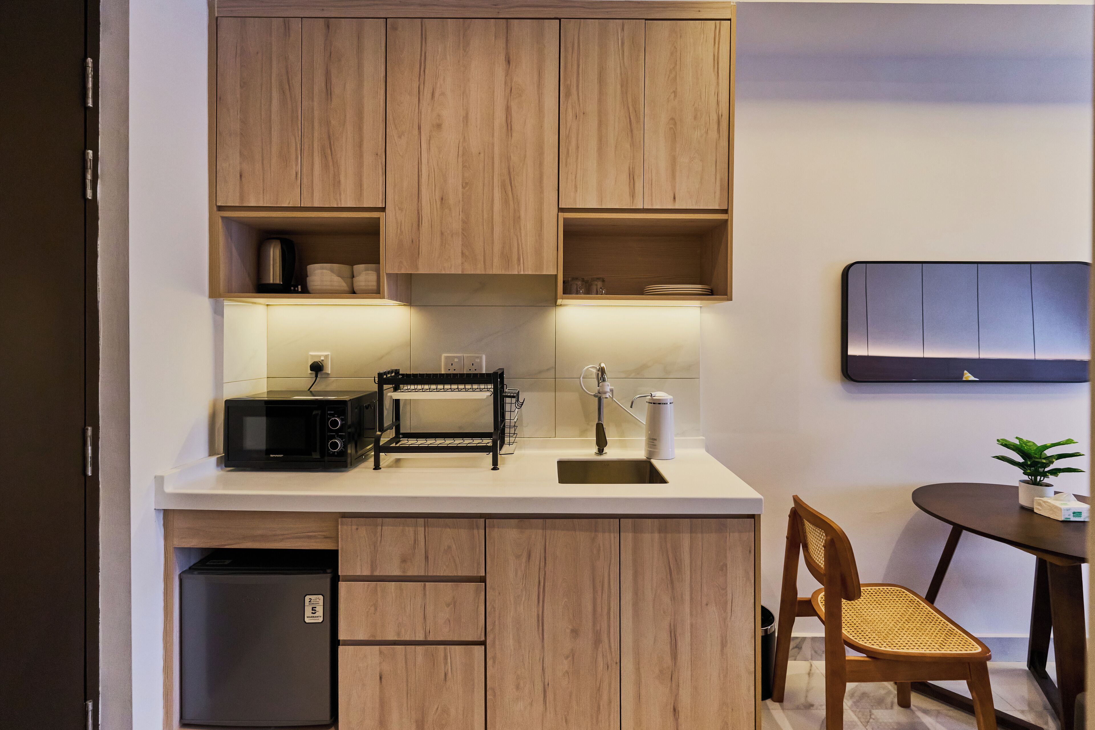 A compact kitchen with wooden cabinets, a microwave, a toaster, and a sink.
