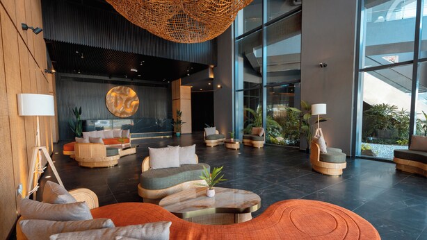 Eine geräumige Lobby mit modernen Sitzgelegenheiten, einem großen abstrakten Wandbild und Blick ins Freie durch große Fenster.