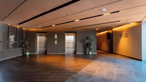 Eine geräumige Lobby mit Holzboden, einer Rezeption und Zimmerpflanzen.