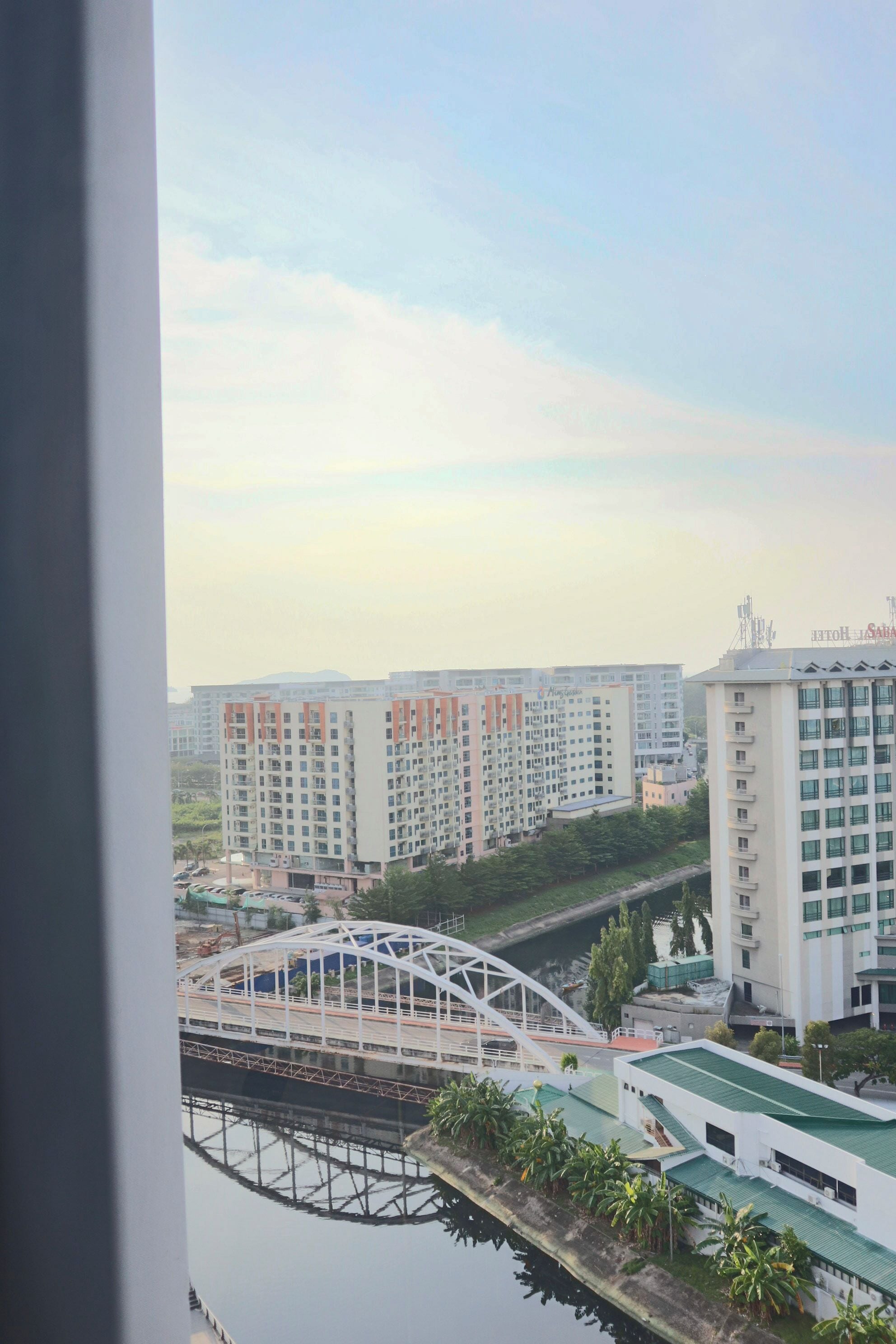 Vista de un moderno edificio de apartamentos con varios pisos, un puente y una masa de agua.