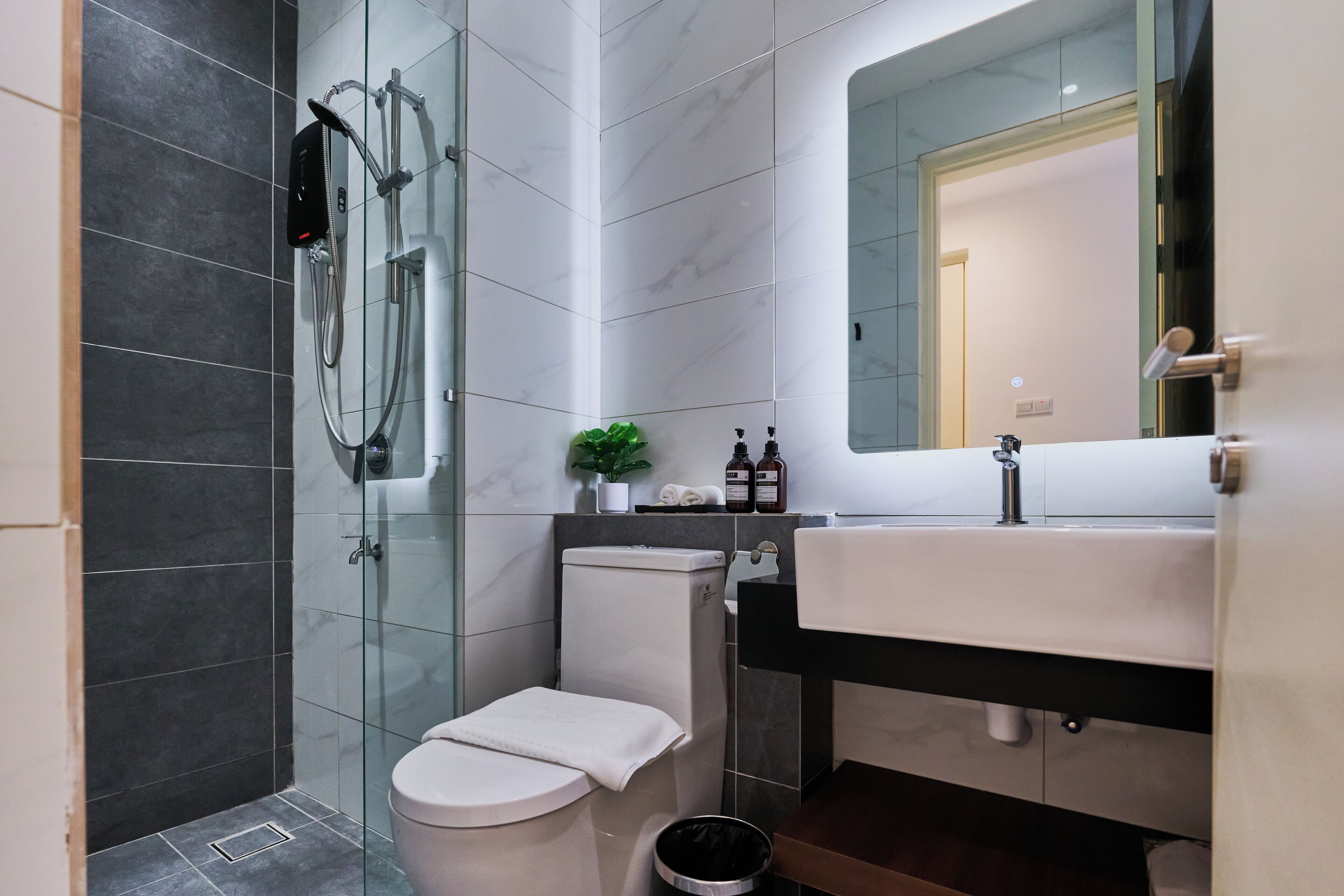 Un bany modern amb dutxa de vidre, un vàter, un lavabo i un mirall.