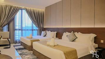 A hotel room with two beds, a sofa, a small table, and a view of the sea.