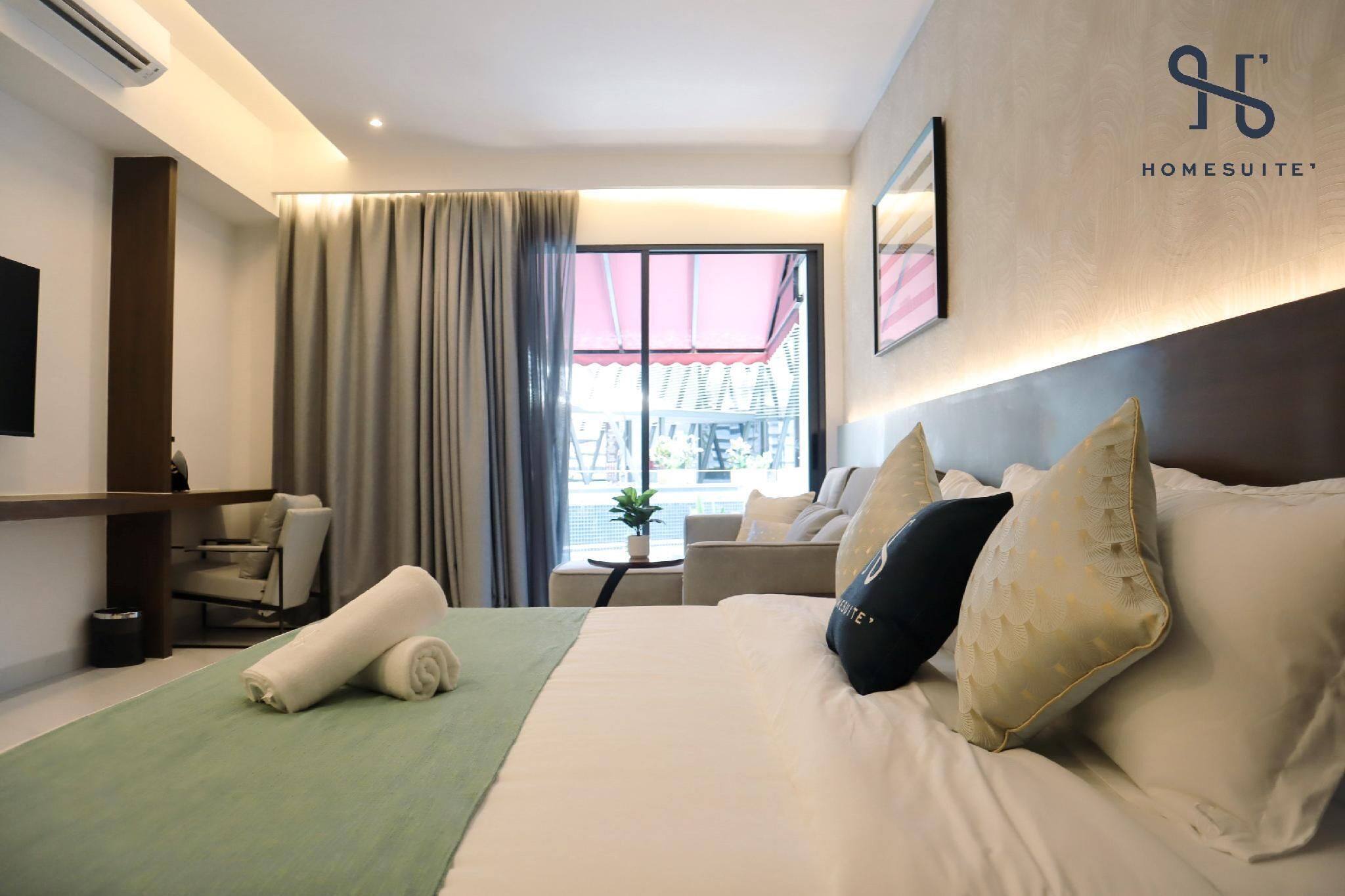 A hotel room with a bed, a desk, a chair, and a window with curtains.