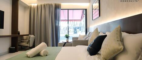 A hotel room with a bed, a desk, a chair, and a window with curtains.