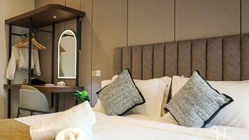 A hotel room with a bed, a desk, a chair, a hanging coat rack, and a mirror.