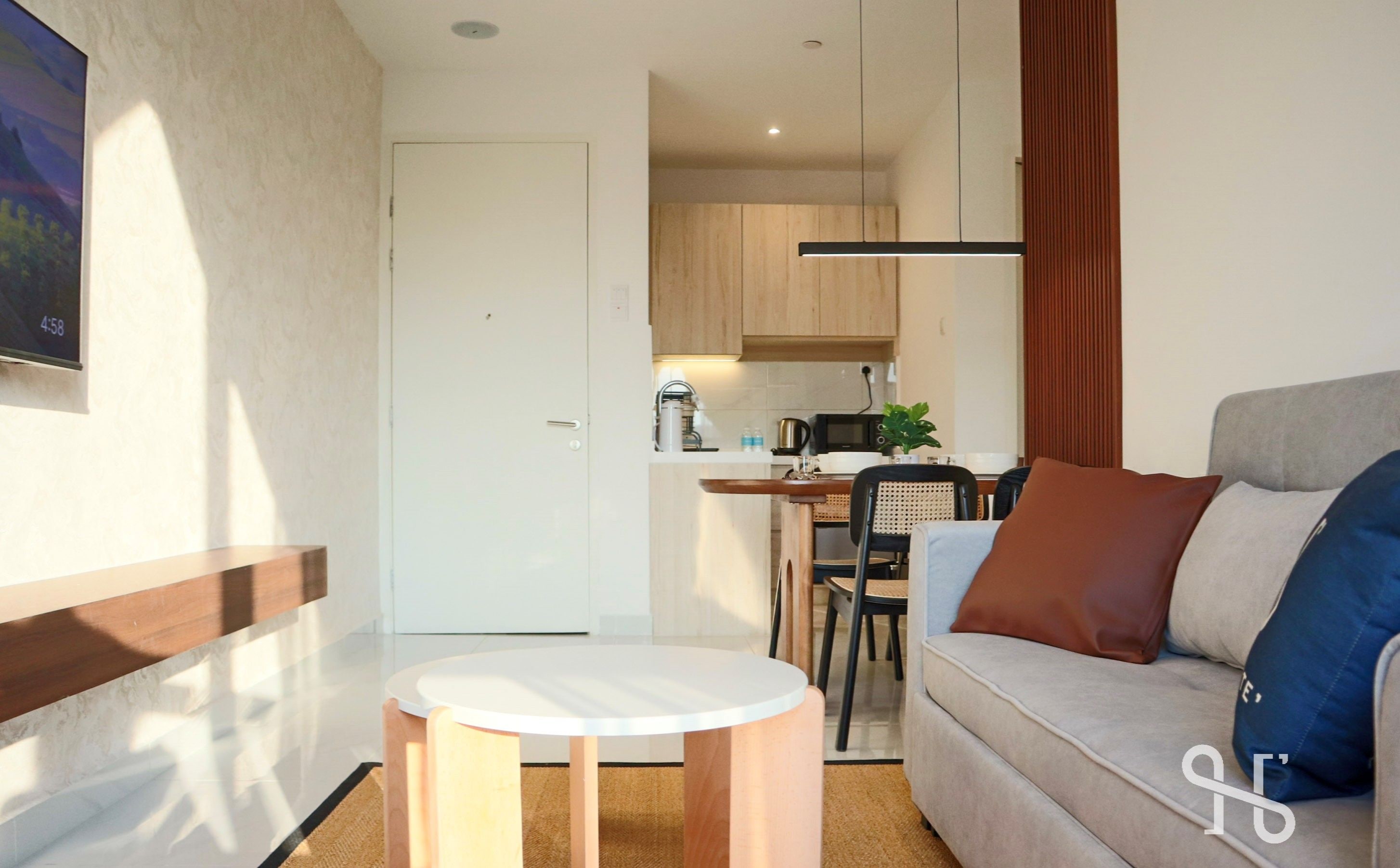 A modern living room with a sofa, a small round table, and a TV mounted on the wall.