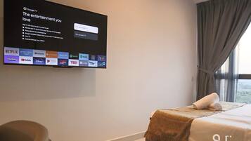 A hotel room with a flat-screen TV mounted on the wall displaying a Google TV interface.