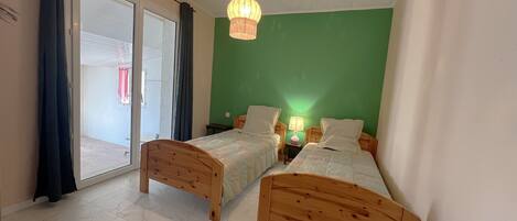 A room with two wooden beds, a green wall, and a ceiling with a geometric pattern.