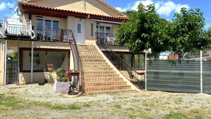 Ein zweistöckiges Haus mit rotem Ziegeldach, einem Balkon und einer Treppe, die zum oberen Stockwerk führt.