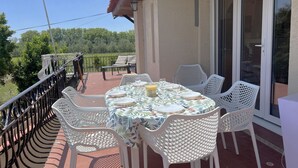 Ein Balkon mit Esstisch, weißen Stühlen und Blick ins Grüne.